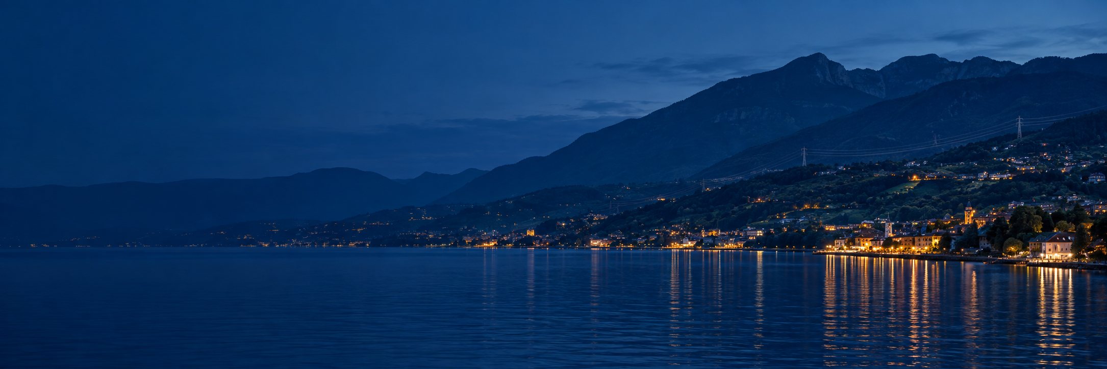 Vallée et lac au crépuscule, lumières d’une ville et ligne électrique